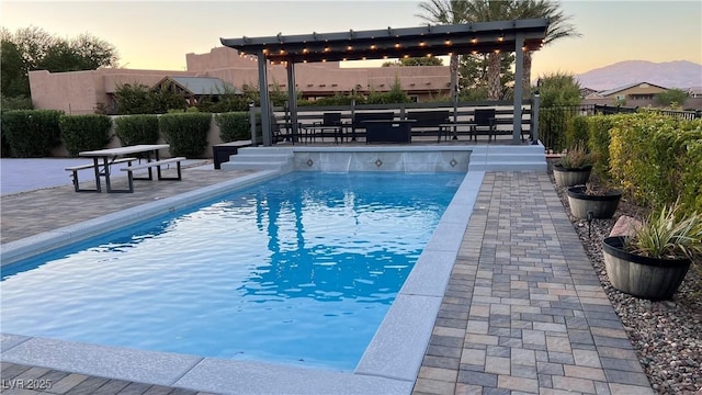 pool at dusk with a patio area