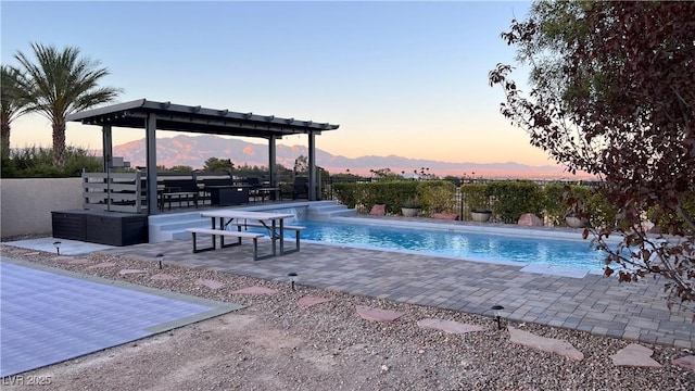 pool at dusk featuring a gazebo and a patio area