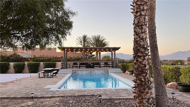 pool at dusk featuring a mountain view, a gazebo, and a patio area