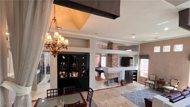 living room featuring crown molding, a healthy amount of sunlight, a fireplace, and an inviting chandelier