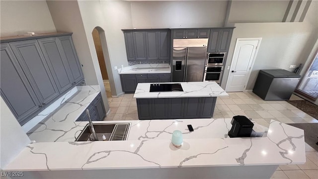 kitchen featuring black stovetop, gray cabinets, built in fridge, and a kitchen island