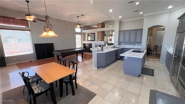 kitchen with black electric stovetop, kitchen peninsula, light stone countertops, and a wealth of natural light