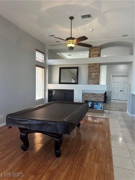 game room with a stone fireplace, light hardwood / wood-style flooring, billiards, and ceiling fan