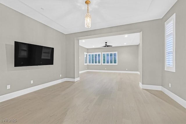 unfurnished living room with a healthy amount of sunlight, light wood-style floors, ceiling fan, and baseboards