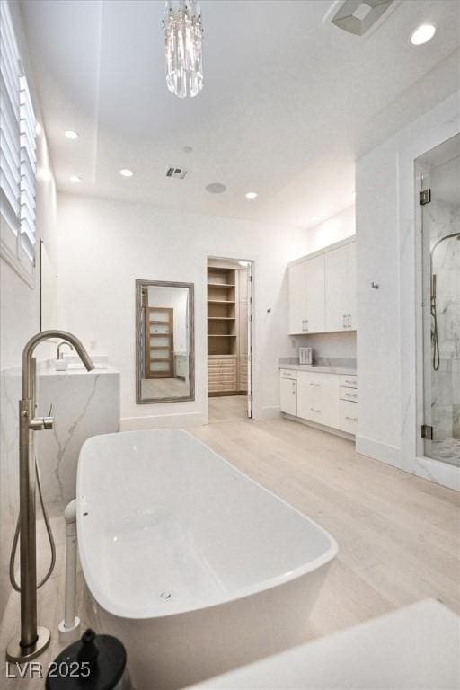 bathroom featuring a marble finish shower, recessed lighting, visible vents, vanity, and wood finished floors