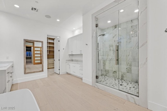 full bath with a stall shower, visible vents, wood finished floors, and vanity