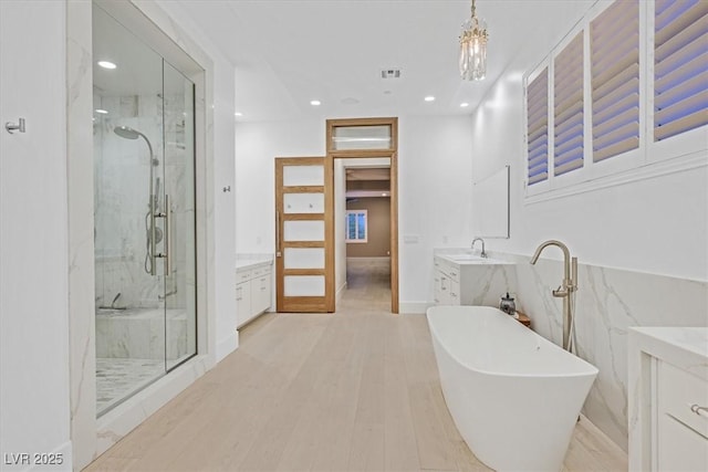 bathroom featuring a freestanding tub, vanity, a marble finish shower, and wood finished floors