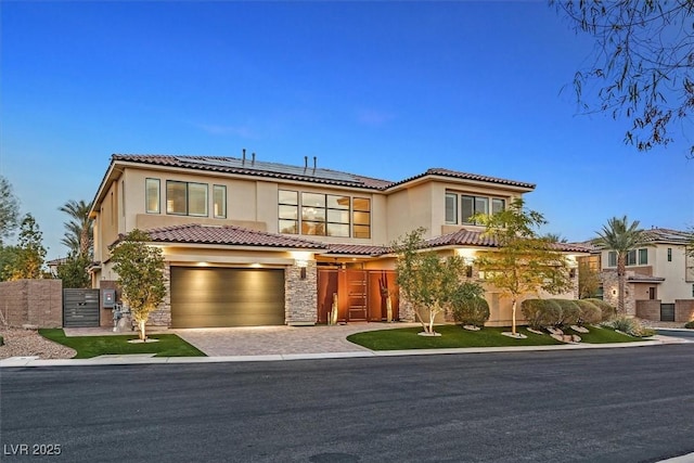 view of front of property featuring a garage, stone siding, decorative driveway, and stucco siding