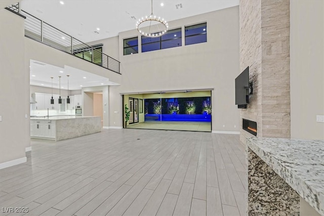 living area with a large fireplace, light wood finished floors, recessed lighting, and baseboards