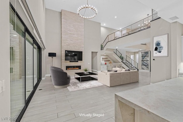 living area with a large fireplace, stairway, wood finished floors, an inviting chandelier, and recessed lighting