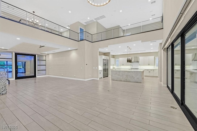 unfurnished living room featuring baseboards, a sink, light wood finished floors, and an inviting chandelier