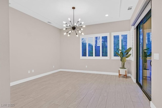 spare room with light wood-type flooring, visible vents, and baseboards