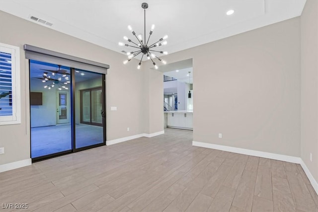 unfurnished room featuring visible vents, a notable chandelier, baseboards, and wood finished floors