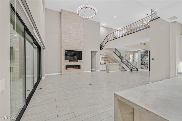 living area featuring a large fireplace, baseboards, wood finished floors, stairs, and a notable chandelier