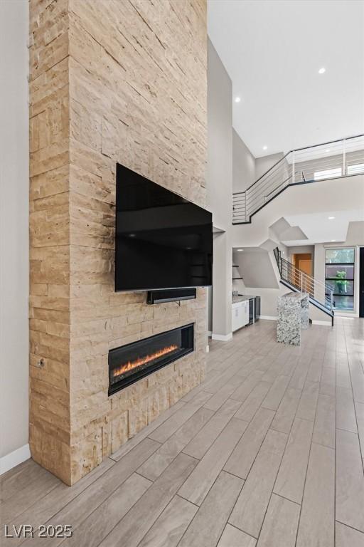 unfurnished living room featuring baseboards, stairs, wood finish floors, a fireplace, and recessed lighting