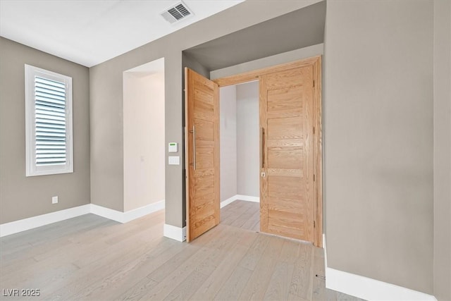 unfurnished bedroom featuring visible vents, light wood-style flooring, and baseboards