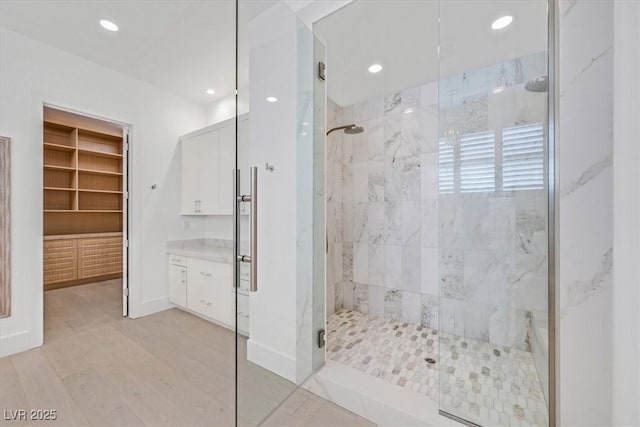 bathroom with recessed lighting, vanity, baseboards, a marble finish shower, and a walk in closet