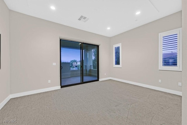 carpeted empty room featuring recessed lighting, visible vents, and baseboards