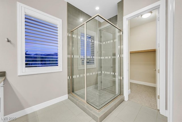 bathroom with a shower stall, a spacious closet, baseboards, and tile patterned floors