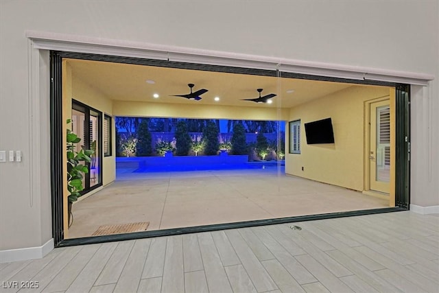 view of patio with a garage, ceiling fan, and an outdoor pool