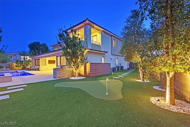 rear view of property featuring a fenced in pool, a balcony, a fenced backyard, a patio area, and stucco siding