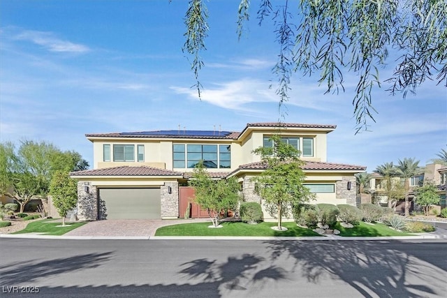 mediterranean / spanish-style home with driveway, stone siding, a tiled roof, roof mounted solar panels, and stucco siding