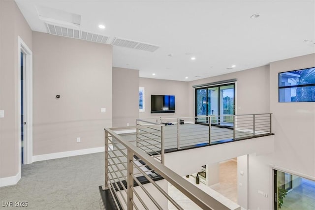 hall featuring baseboards, visible vents, and an upstairs landing