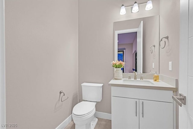 bathroom featuring tile patterned flooring, baseboards, vanity, and toilet