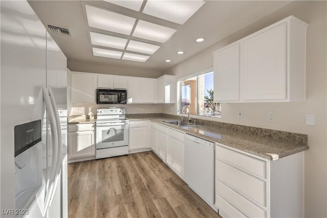 kitchen featuring sink, white cabinetry, light wood-type flooring, white appliances, and light stone countertops