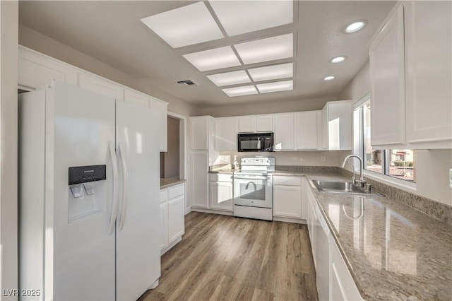 kitchen with sink, white cabinets, light stone counters, white appliances, and light hardwood / wood-style flooring