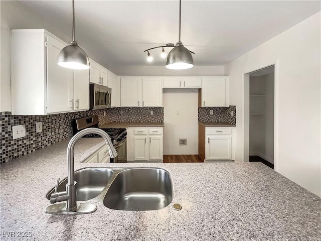 kitchen with white cabinets, backsplash, appliances with stainless steel finishes, and a sink