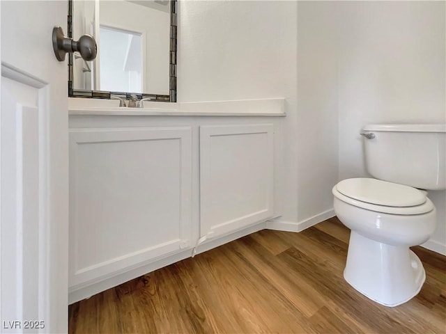 bathroom with toilet, vanity, baseboards, and wood finished floors