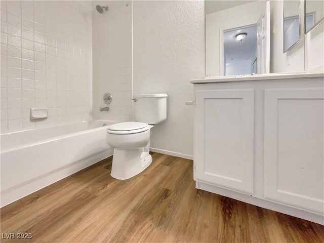 bathroom with vanity, wood finished floors, baseboards, shower / washtub combination, and toilet