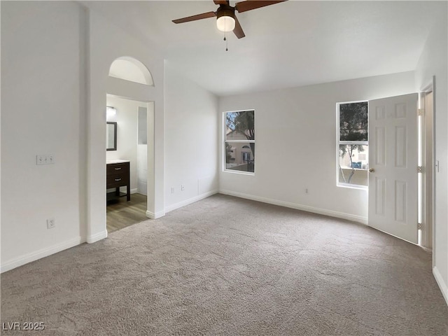 unfurnished bedroom featuring connected bathroom, baseboards, carpet, ceiling fan, and lofted ceiling