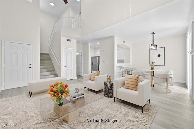 living room featuring a towering ceiling and light hardwood / wood-style floors