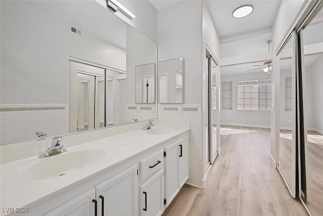 bathroom with tile walls, vanity, wood-type flooring, and ceiling fan