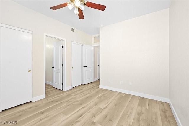 unfurnished bedroom featuring ceiling fan, two closets, and light wood-type flooring