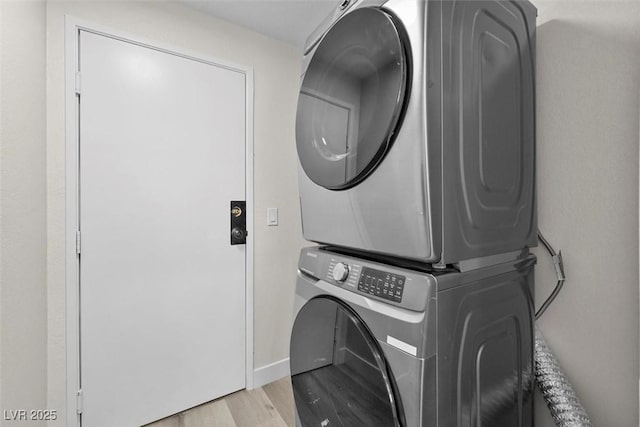 laundry room featuring stacked washer / drying machine and light hardwood / wood-style flooring