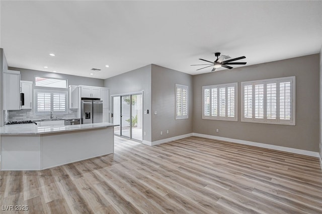 kitchen featuring appliances with stainless steel finishes, light wood-type flooring, decorative backsplash, and white cabinets