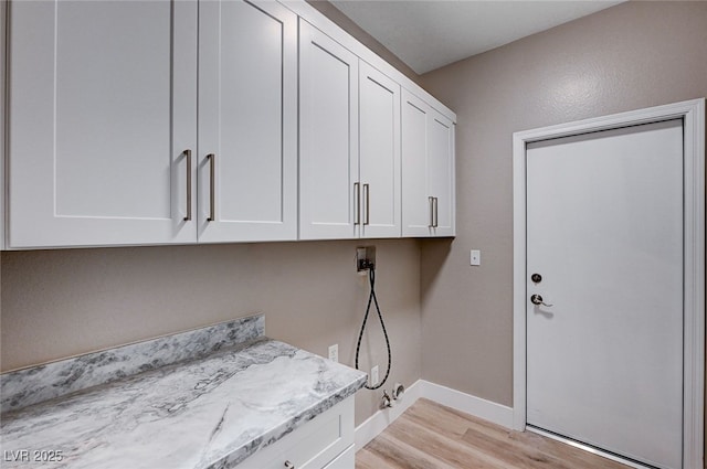 washroom with cabinets, hookup for a washing machine, and light hardwood / wood-style flooring