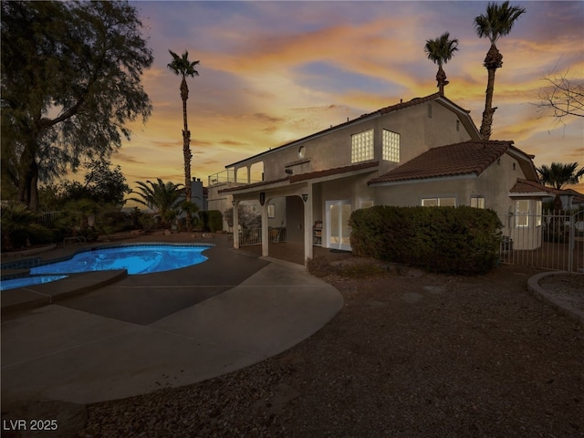 pool at dusk featuring a patio