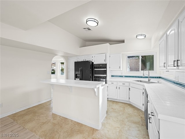 kitchen featuring white cabinetry, a kitchen island, tile counters, and black appliances