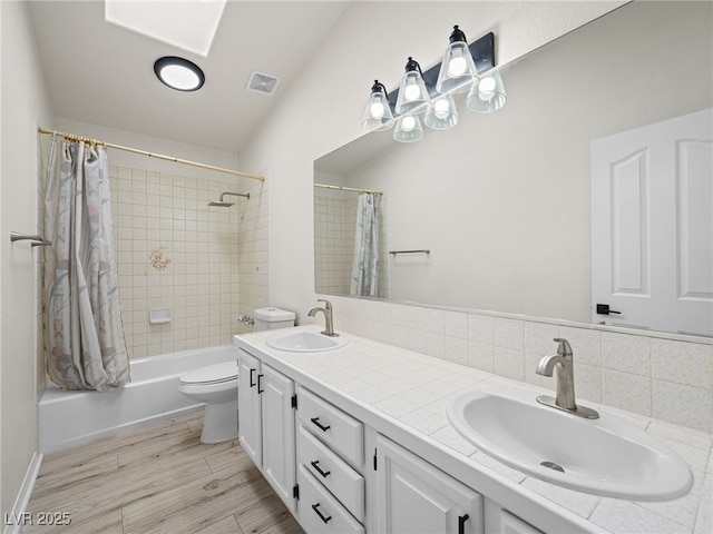 full bathroom with hardwood / wood-style flooring, vanity, shower / bathtub combination with curtain, and toilet