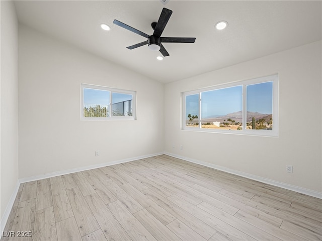 unfurnished room featuring vaulted ceiling, a mountain view, ceiling fan, and light wood-type flooring