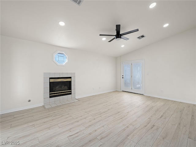 unfurnished living room featuring a tiled fireplace, lofted ceiling, ceiling fan, and light hardwood / wood-style flooring