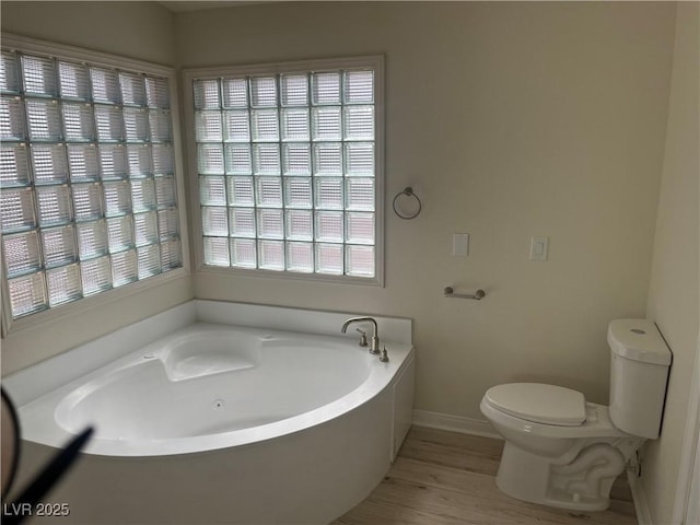 bathroom featuring a tub to relax in, hardwood / wood-style floors, and toilet