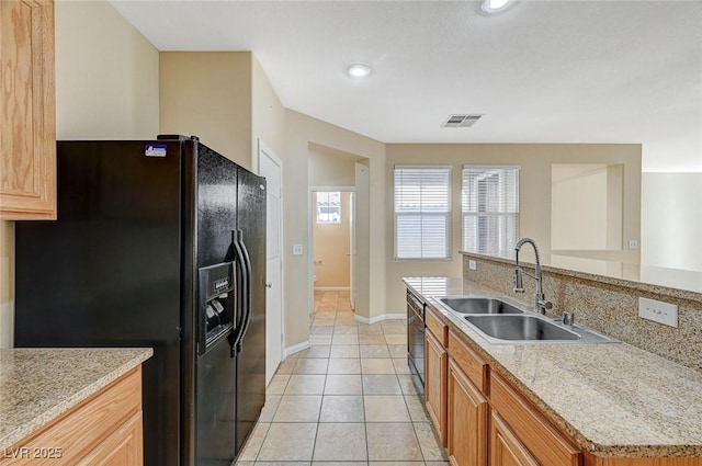 kitchen with light tile patterned flooring, sink, light stone counters, and black appliances