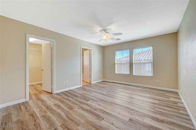 unfurnished bedroom featuring ensuite bathroom, a walk in closet, a closet, and light wood-type flooring