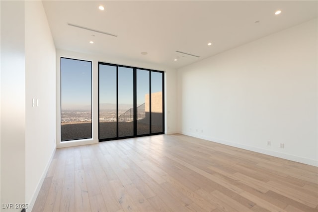 unfurnished room featuring expansive windows and light hardwood / wood-style floors