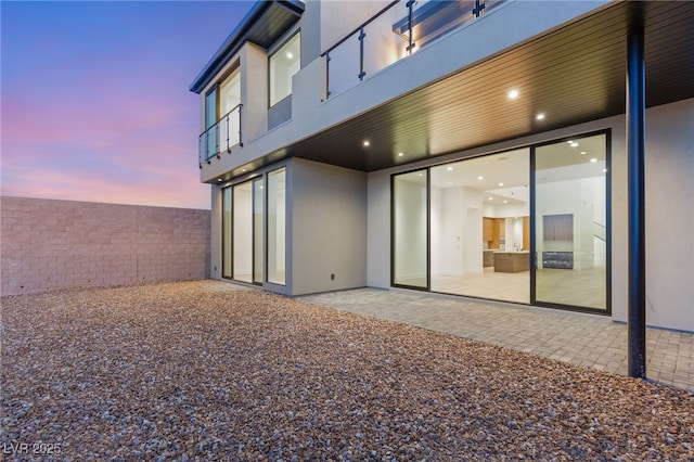 back house at dusk featuring a patio area